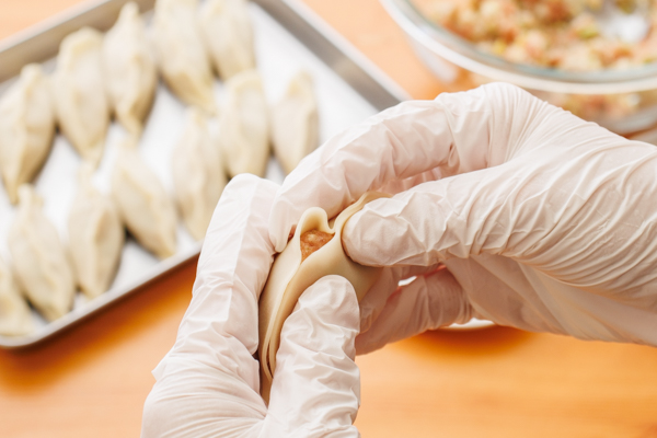 餃子の皮の中央に肉だねをのせ、ふちに水少々(分量外)をつける。皮を半分に折り、ひだを寄せながら包む。※大阪王将の餃子はひだが1つ